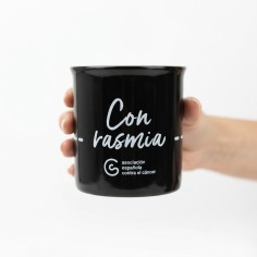 Taza solidaria negra con el lema Con Rasmia de la AECC sobre superficie neutra